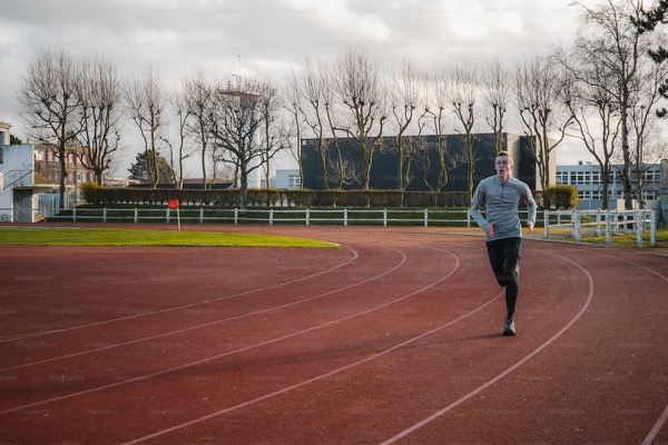 Runner on an athletics track with trees in the background
