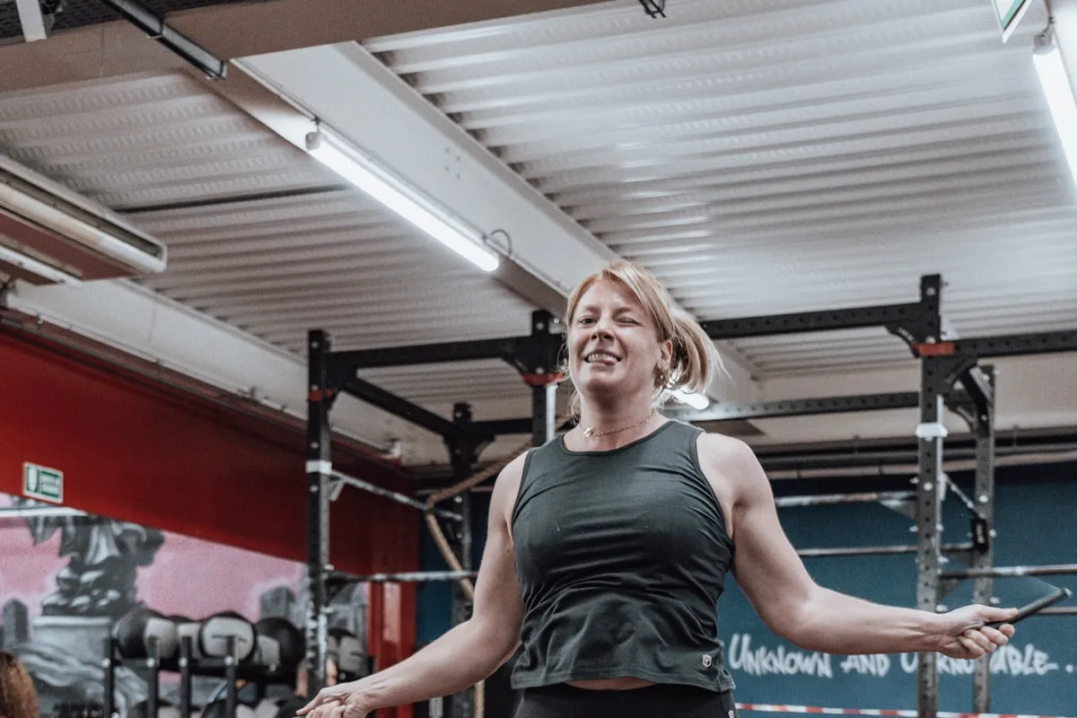 Woman in mid-air during a jumping HIIT exercise inside a gym