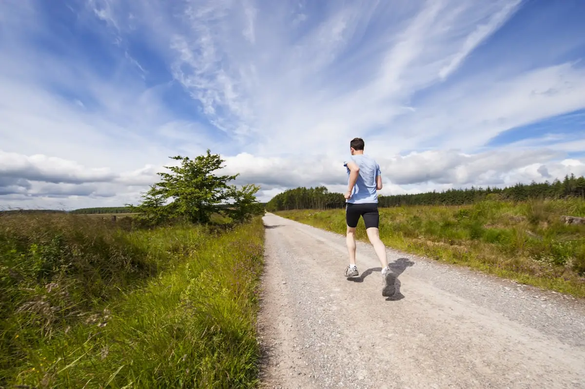 Runner mid-stride on an open country road under a wide sky