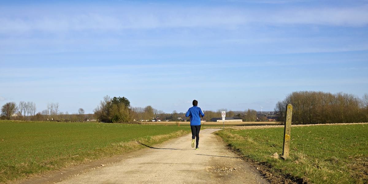 Runner on an outdoor path through green fields