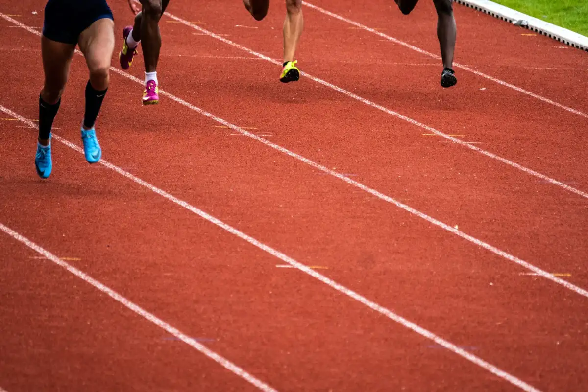 Sprinters at full effort on an outdoor running track, legs captured mid-stride